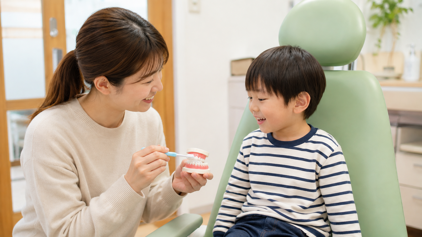 お母さんが小さな歯の模型に歯ブラシを当て、お子様へ歯みがきを教える様子