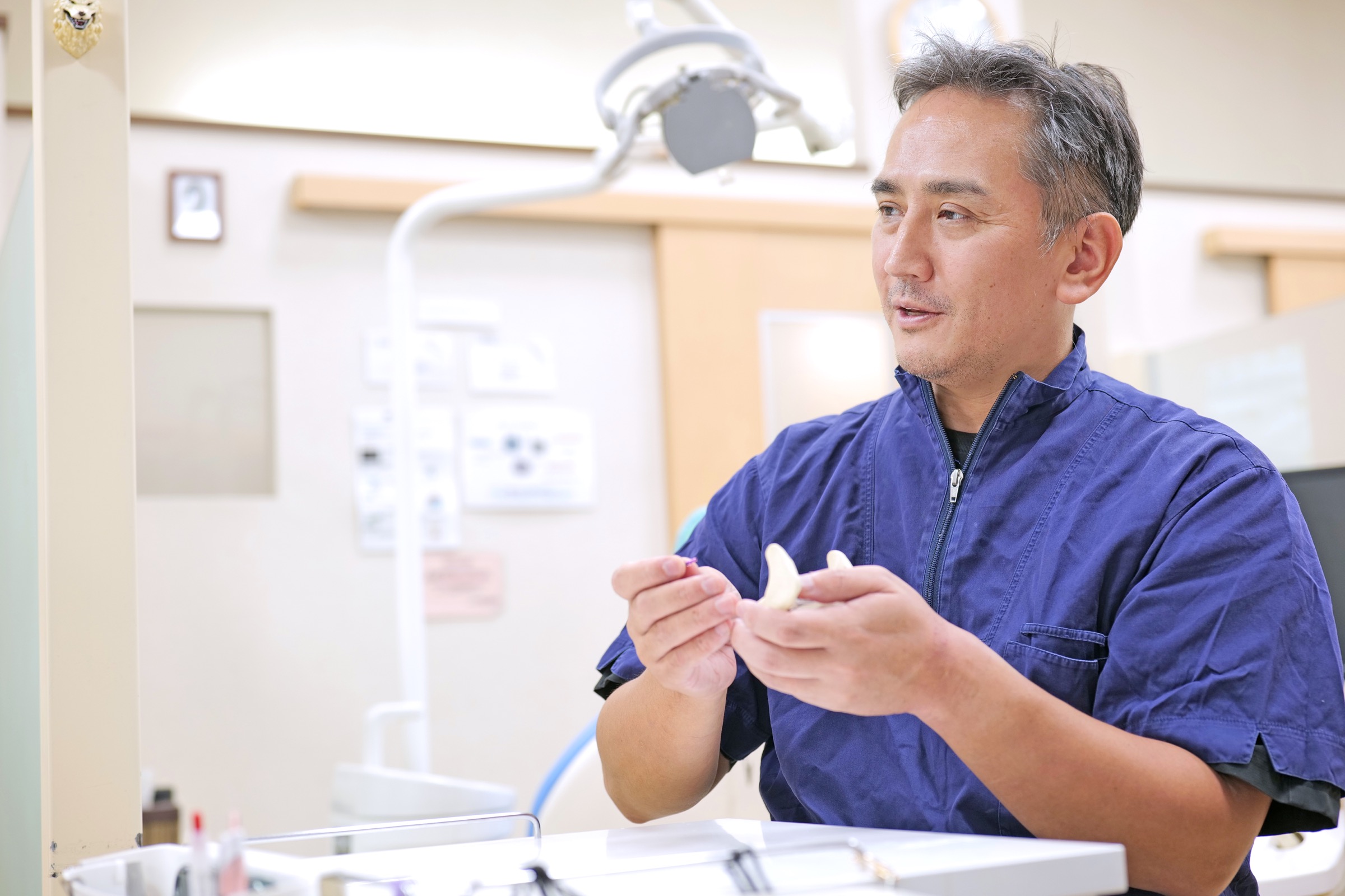 院長がインプラント模型を手に治療方法を説明する様子